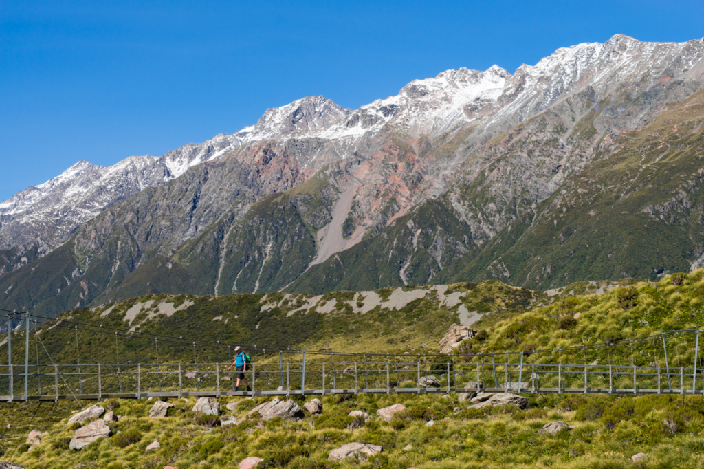 A hiker crosses one of three swing bridges on the Hooker Valley Track in Mt. Cook National Park.