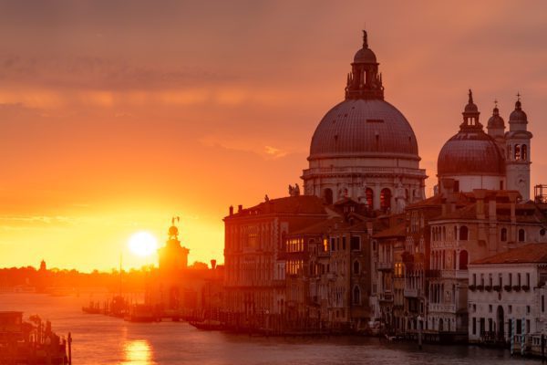 This image captures a breathtaking sunset over the Grand Canal in Venice, Italy, with the iconic silhouette of Santa Maria della Salute basilica.