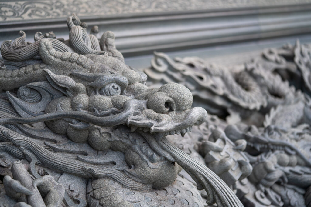 Intricately carved stone dragon sculpture on an ancient temple wall, showcasing detailed craftsmanship and cultural artistry in relief style.