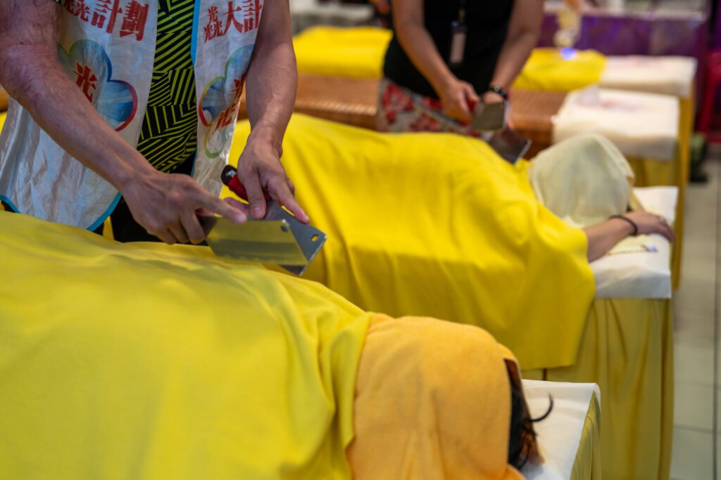 Close-up of Taiwanese practitioner performing traditional knife massage therapy with blunt knives.